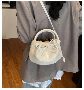 Chic beige bucket bag with drawstring bow and smooth texture worn in a cozy room setting