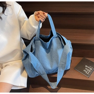 Detail view of large blue washed denim tote bag with soft fabric and wide shoulder strap