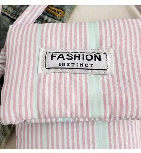 Detailed close-up of striped fabric phone bag with Fashion Instinct woven label on front