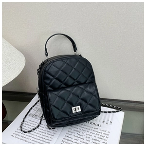 Detail of black quilted PU leather backpack with silver metal turn-lock and chain strap