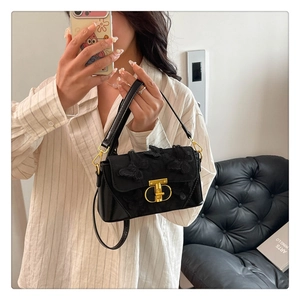 Detail of elegant black bag featuring 3D butterfly embroidery and gold metal clasp