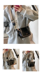 Close-up of black leather crossbody bag with wide jacquard strap and gold stud details