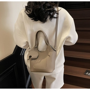 Detail of grey lychee leather bucket bag featuring a cute elephant leather charm and strap