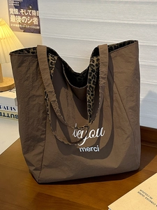 Brown oversized tote bag with leopard print straps and 'be you merci' text design