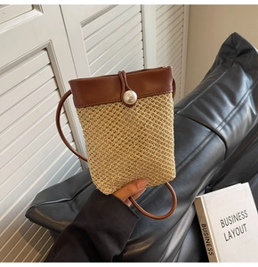Detail of woven straw mini bucket bag with brown leather trim and large pearl clasp