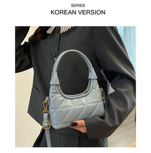 Close-up of quilted light blue underarm bag with gold hardware on grey suit model