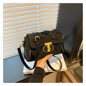 Detail of black crossbody bag with 3D butterfly embroidery and gold T-shape metal clasp