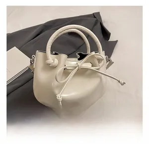 Close-up of a white oil wax leather bucket bag with a stylish front bow and round handle