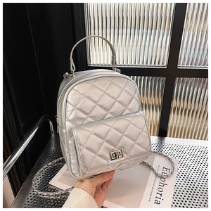 Detail of silver quilted backpack with metallic finish, chain strap and metal turn lock