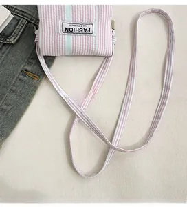 Detail of pink and green striped crossbody phone bag with an adjustable strap and logo patch