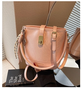 Détail d'un sac seau en cuir rose avec fermoir doré et pendentif de raquette de tennis