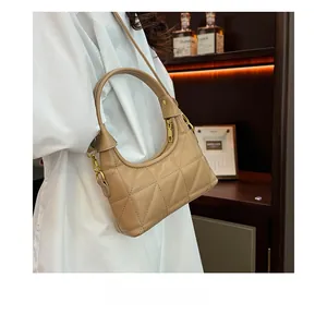 Detail of beige quilted shoulder bag with golden hardware and curved top handle