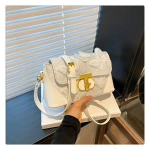 Detail of elegant white crossbody bag with 3D butterfly embroidery and gold metal clasp