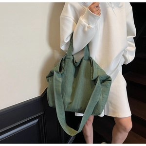 Green canvas tote bag detail showing the wide shoulder strap and soft washed texture