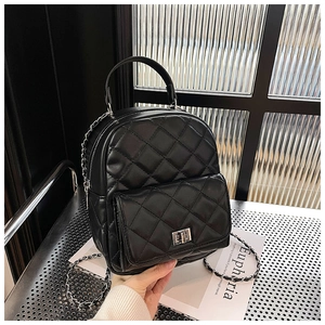 Close-up of black quilted mini backpack with silver turn-lock and chain straps