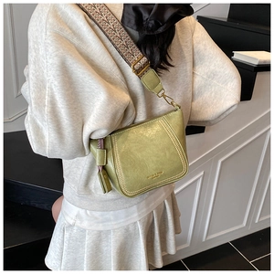 Detail of avocado green leather crossbody bag with ethnic style woven wide shoulder strap