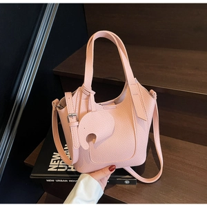 Detailed macro of pink lychee leather texture on bucket bag with elephant pendant charm