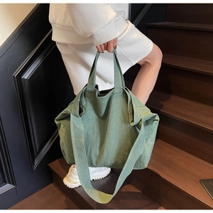 Detail of a large green canvas tote bag with adjustable shoulder straps and carry handles