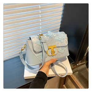 Detail of light blue embroidered butterfly crossbody bag with gold metal lock closure