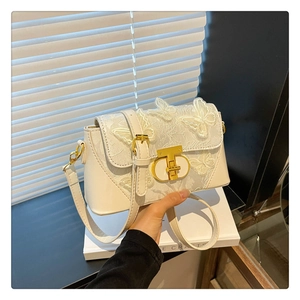 Detailed close-up of 3D butterfly embroidery and gold metal clasp on white square bag