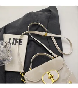 Detailed macro view of the cream leather handbag with an adjustable strap and gold lock