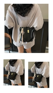 Détail du sac seau noir en cuir avec fermoir doré et foulard en soie décoratif élégant