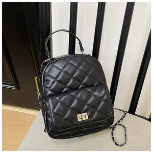 Detailed view of black quilted mini backpack with silver metal twist lock and chain strap