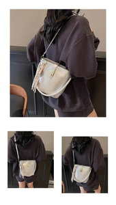 Détail du sac seau argenté avec fermoir doré et accessoire de pompon tissé chic