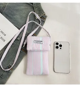 Detailed view of pink striped canvas phone bag with adjustable strap and fashion label