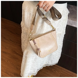 Detail of beige crossbody bag with wide geometric pattern strap and textured PU leather