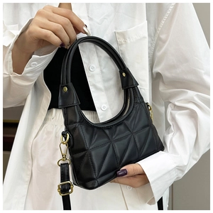 Detail of black quilted underarm bag featuring golden hardware and leather strap