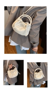 Detail of a creamy white mini bucket bag with a bow accent and polished oil wax leather