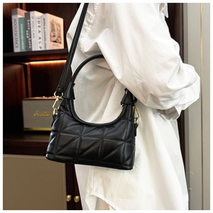 Detail of black quilted shoulder bag featuring soft PU leather and golden metal hooks