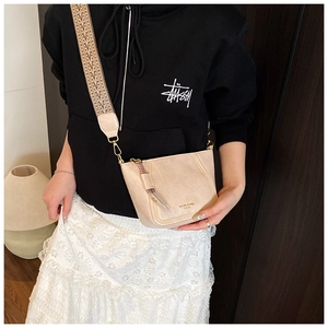 Detail view of beige leather dumpling bag with fringe and geometric print wide strap