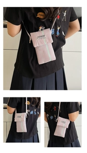 Detailed view of pink striped canvas phone bag with Fashion Instinct label and thin strap