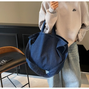 Detailed texture of heavy denim blue tote bag showing clear fabric grain and wide strap