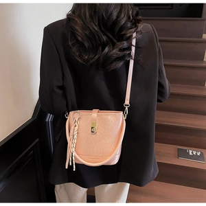 Vue détaillée du sac seau rose corail avec fermoir doré sur une tenue noire