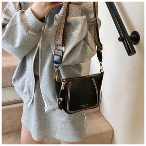 Detail of black PU leather dumpling bag featuring gold studs and wide woven strap