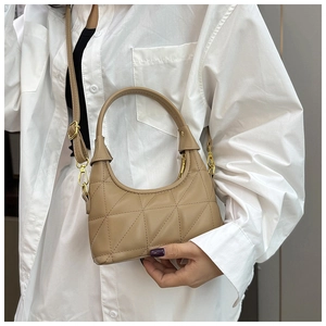 Detail of khaki quilted crossbody bag with geometric stitching and metal hooks on white shirt