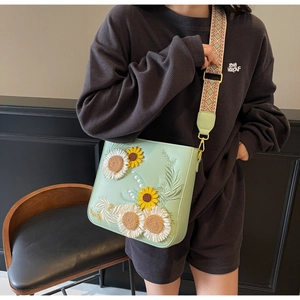 Close-up of 3D floral sunflower embroidery on light green bag with bohemian strap