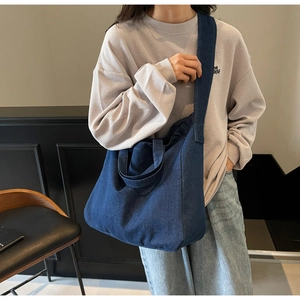 Detail view of a spacious dark blue denim tote bag worn with casual wear for a relaxed look