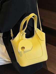 Minimalist yellow lychee leather bucket bag with an elephant charm for women