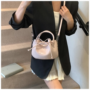 Pink waxed leather bucket bag with bow tie detail shown as a crossbody on model
