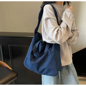 Detailed view of dark blue denim tote bag with long shoulder straps and short handles