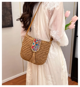 Detail of bohemian straw crossbody bag with colorful beadwork and fringe on white lace dress