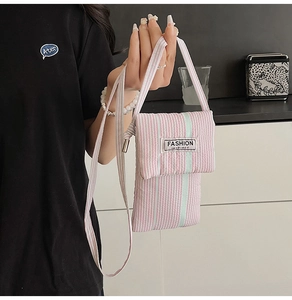 Detail of pink striped crossbody phone bag with soft fabric texture and fashion label