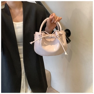 Close-up of pink wax leather bucket bag with decorative bow and smooth glossy finish