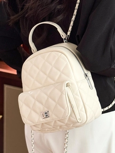 Quilted white mini backpack with silver chain straps shown on model in a side view
