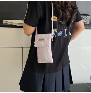 Detailed side view of a pink striped crossbody phone bag with a fashion fabric label