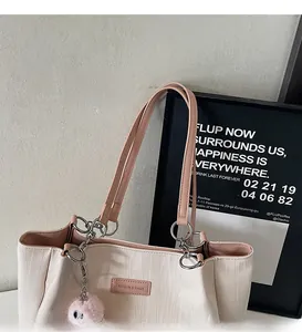 Close-up of cream tote bag with pink straps and fashion label detail on textured faux leather